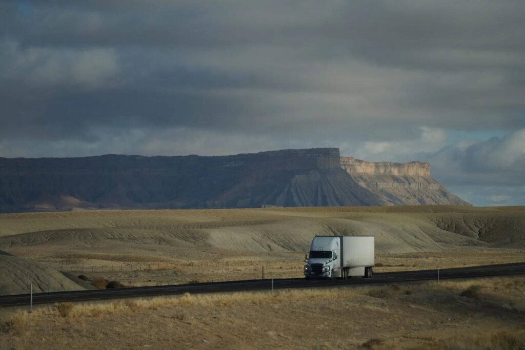 Box truck driving on a US desert highway past mesas