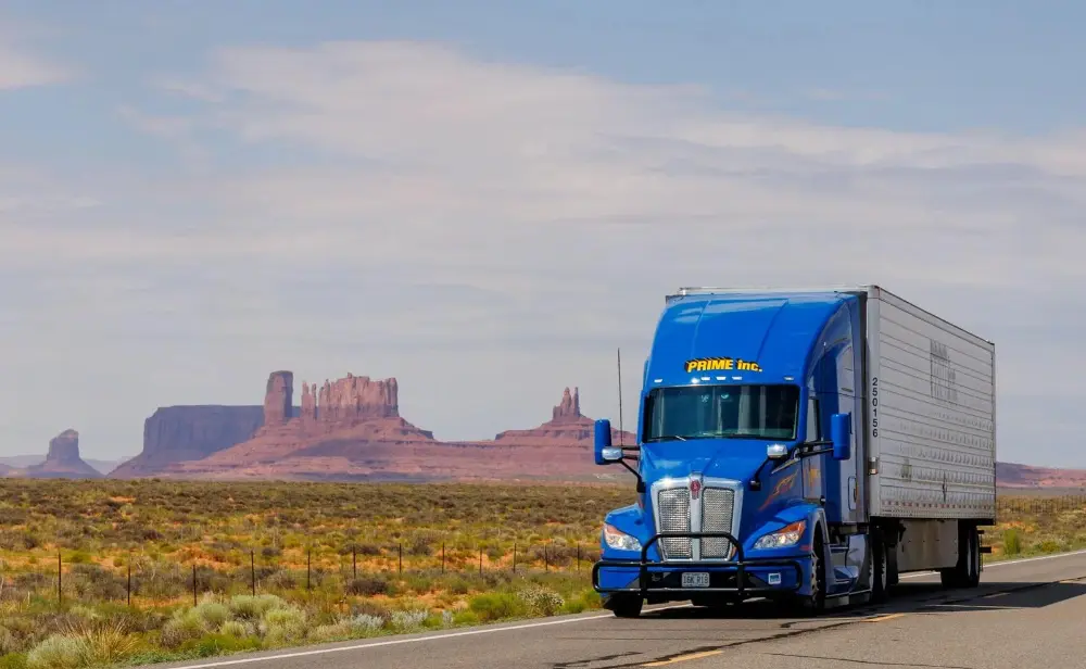 Blue semi truck driving past Monument Valley on a US highway