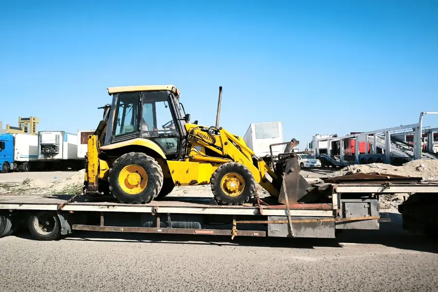 Backhoe loader secured on a lowboy trailer for heavy haul transport